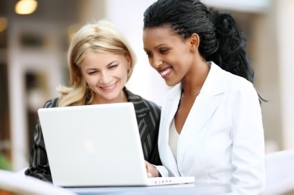 Interracial businesswomen working on laptop.