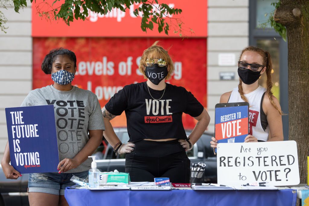 women-wearing-masks-pose-behind-a-voter-registration-table-news-photo-1597785577-2